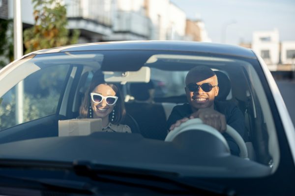 Multiracial couple riding in car at sunny day